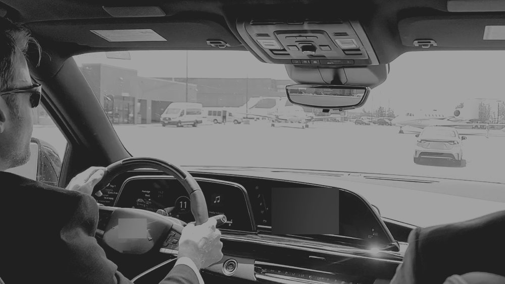 A principal being driven through a city street in a high-risk country, seen from the rear seat