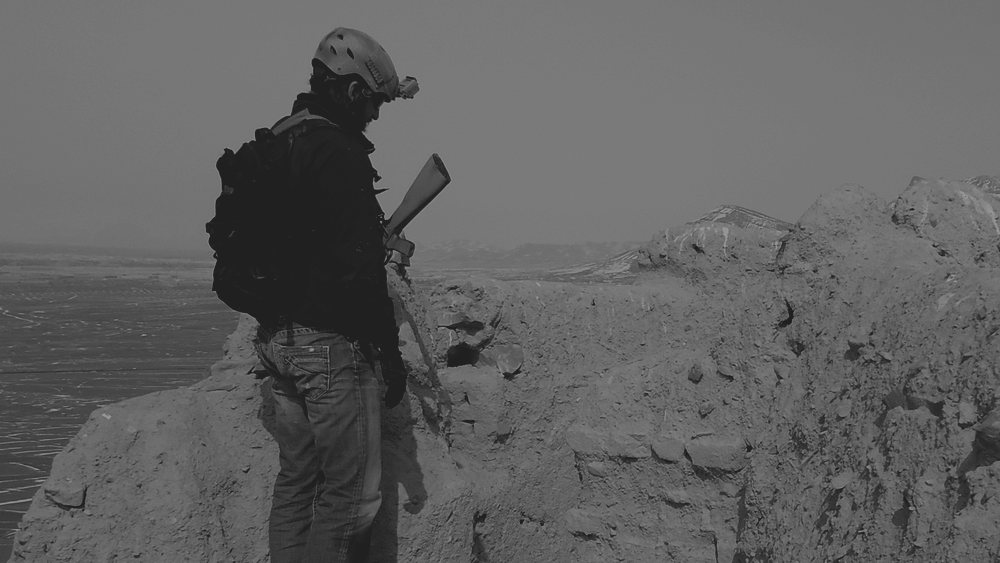 A protective operator standing on a wall above open ground, watching the approaches
